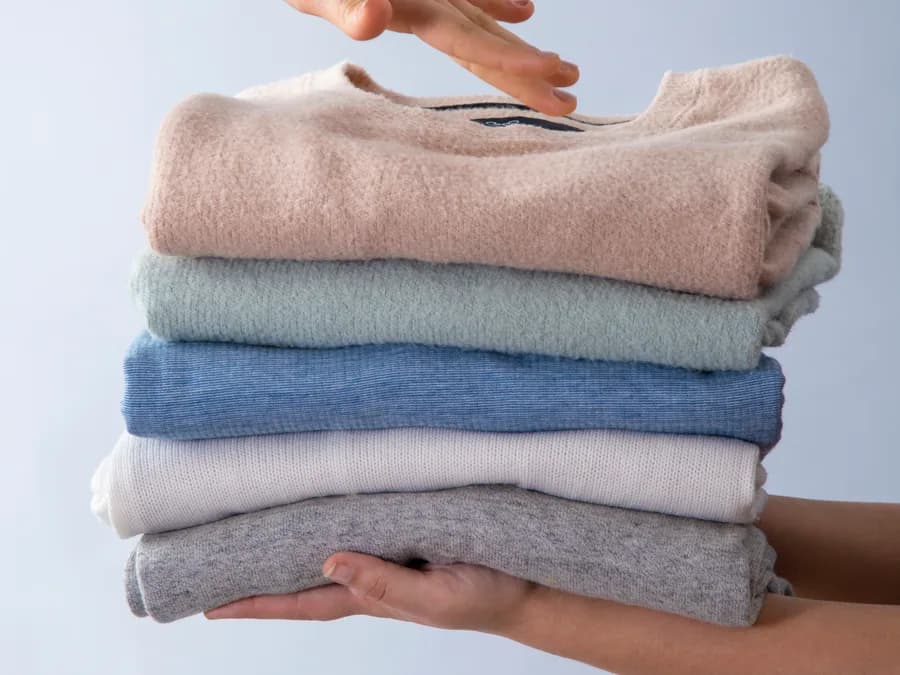 A folded stack of clean clothes held in two hands